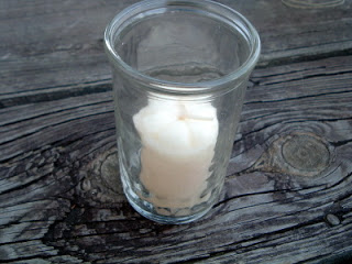 glass with votive candle on aged wood