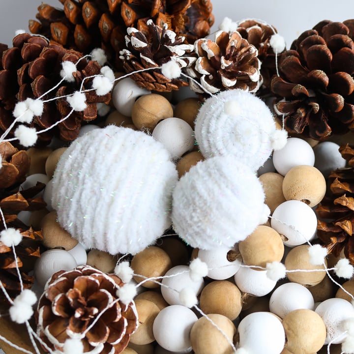 DIY fake snowballs in a bowl with beads and pinecones