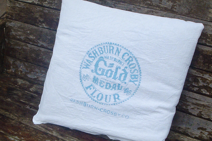 Vintage gold medal flour logo added to a pillow with a stencil cut on the Cricut machine.