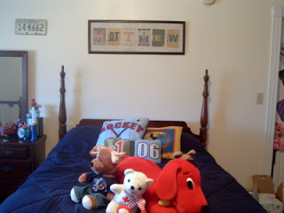 boys bed with navy comforter, stuffed animals and wall art over bed