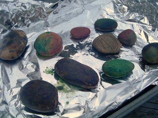 crayon wax coated rocks on a baking sheet lined with aluminum foil