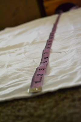 measuring tape on white sheet on top of carpet