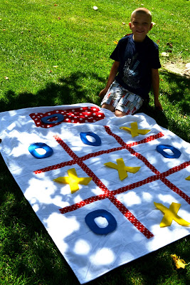 young boy next to tic tac toe game on grass
