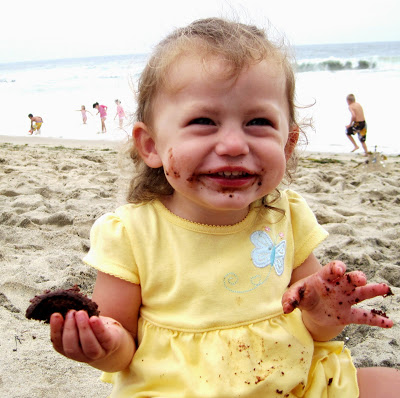 little girl wearing yellow eating cookies on beach