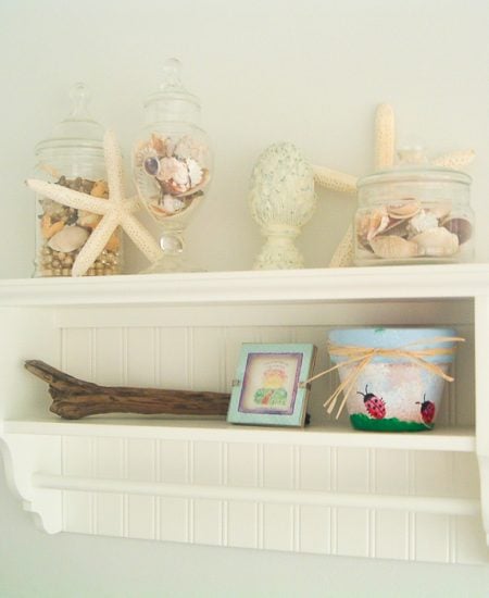 Shelf in a beach themed bathroom with starfish and seashells.