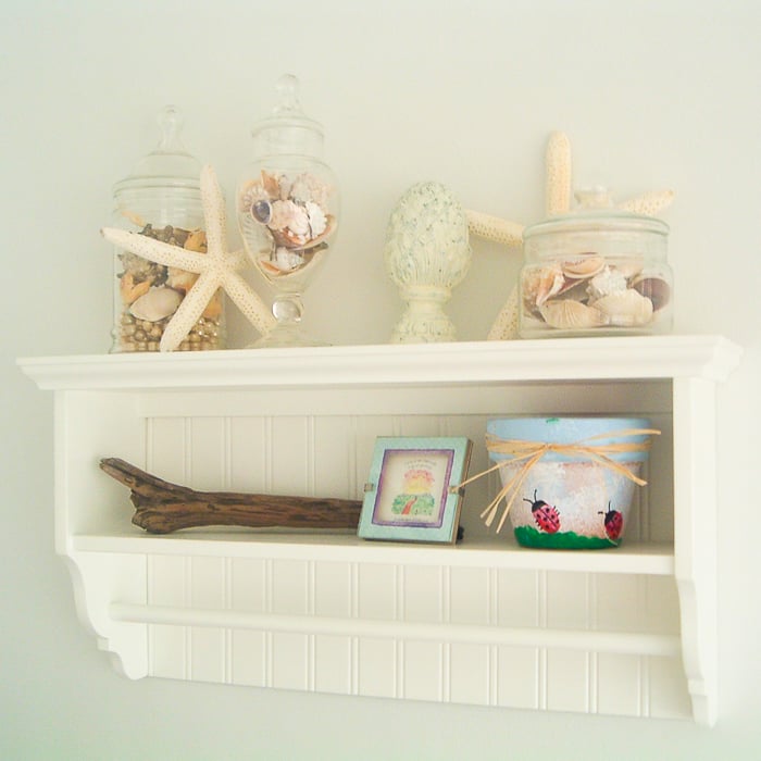 Shelf in a beach themed bathroom with starfish and seashells.