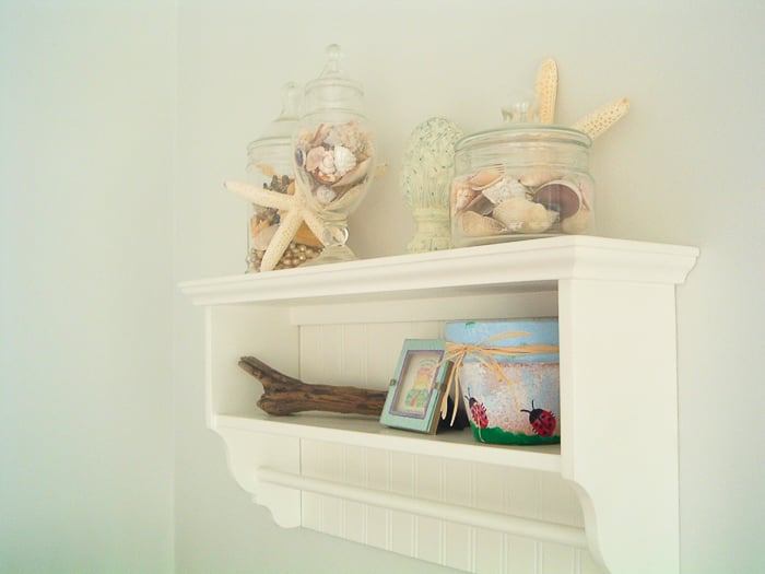 Coastal themed bathroom decor on a shelf including starfish and shells.