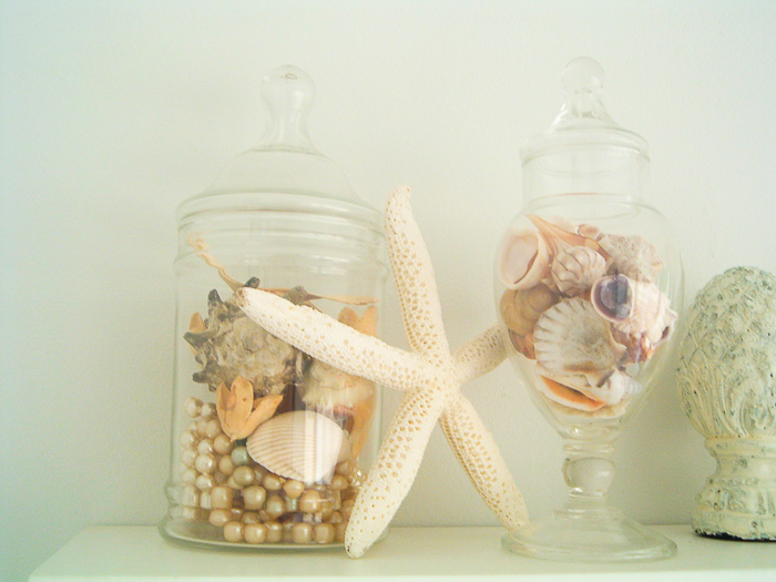 Beach theme bathroom decor including apothecary jars with shells.