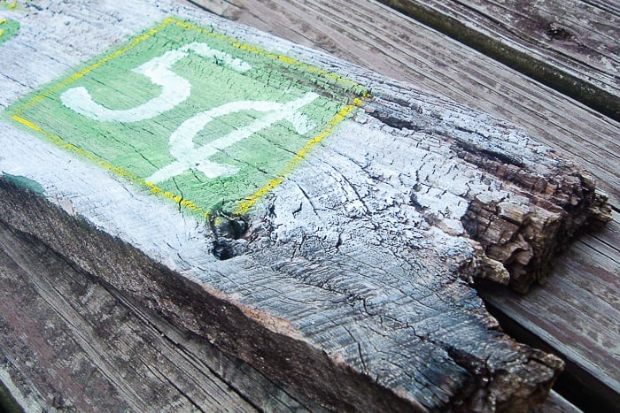 Close up of weathered wood and 5 cent portion of the sign.