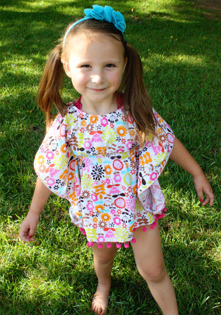 little girl in yard wearing floral cover up