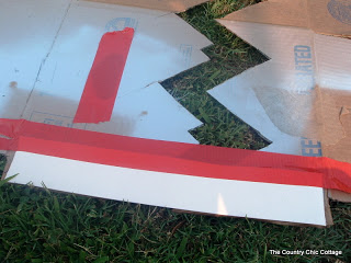 taping cardboard together with red tape to make a chevron stencil