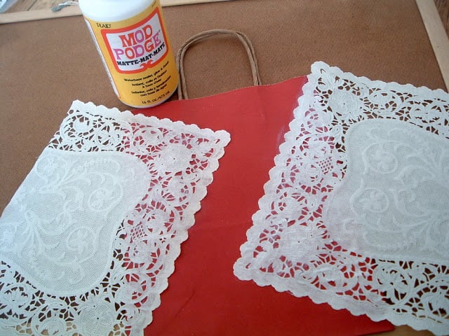 doilies and red gift bag next to bottle of mod podge