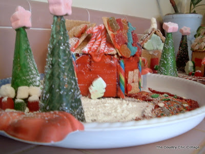 Gingerbread house in a shallow bowl with two green trees