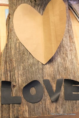 Paper heart and letters laid on top of barn wood