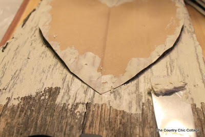 Painting heart shape with white paint onto barn wood