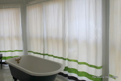 green and blue striped curtains behind a claw foot tub