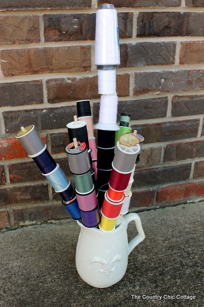 spools of threads on wooden dowel rods in pitcher