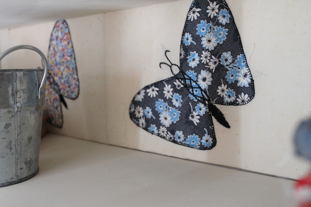 blue and back butterfly fabric square in the back of vintage armoire