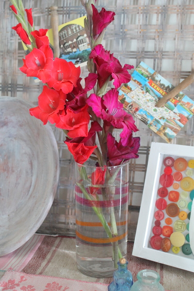 painted striped vase with orange and purple flowers and postcards
