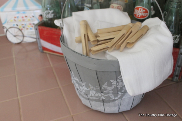 gray basket holding flour sack towels and wooden clothespins
