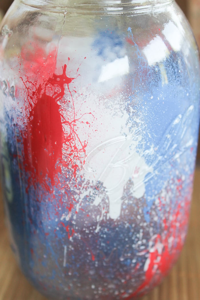 Splattered red, white, and blue paint looks like fireworks inside this painted mason jar!