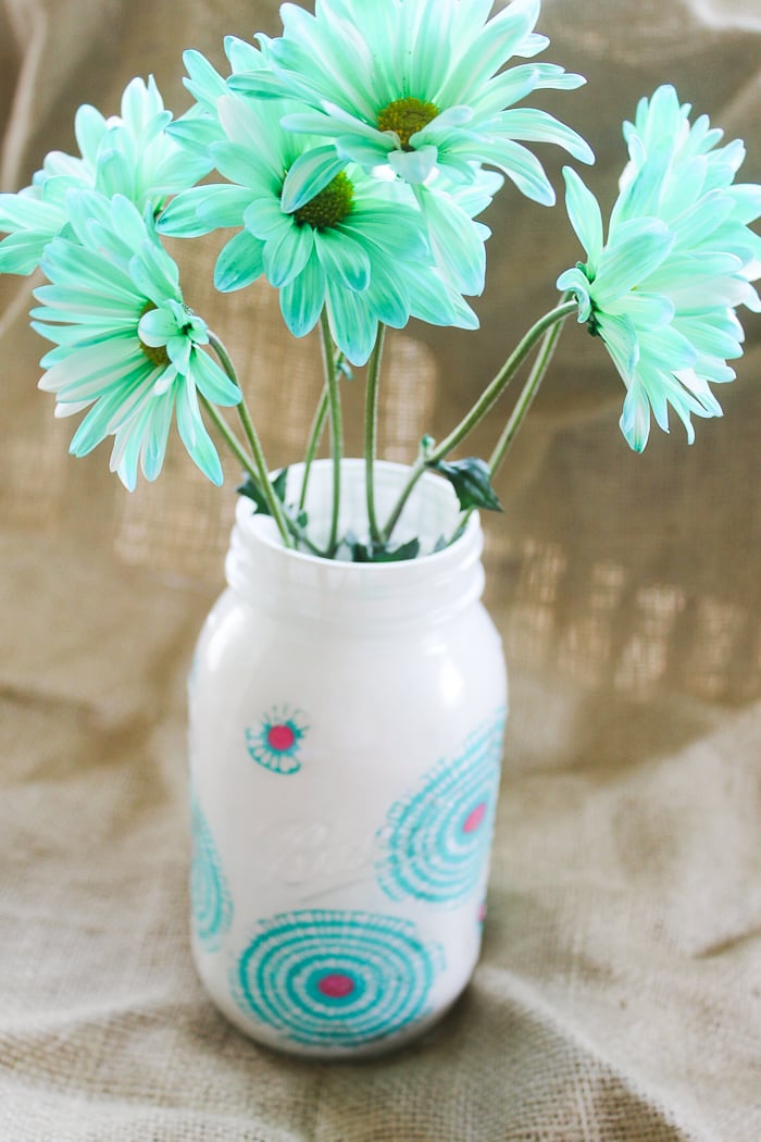 Flowers inside a decorated jar with fabric and paint.