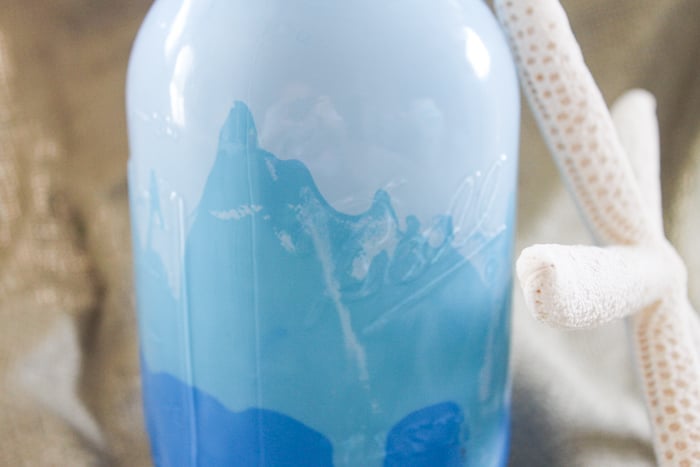 Allow the mason jar to stand upright as the ombre blue paint dries inside the jar