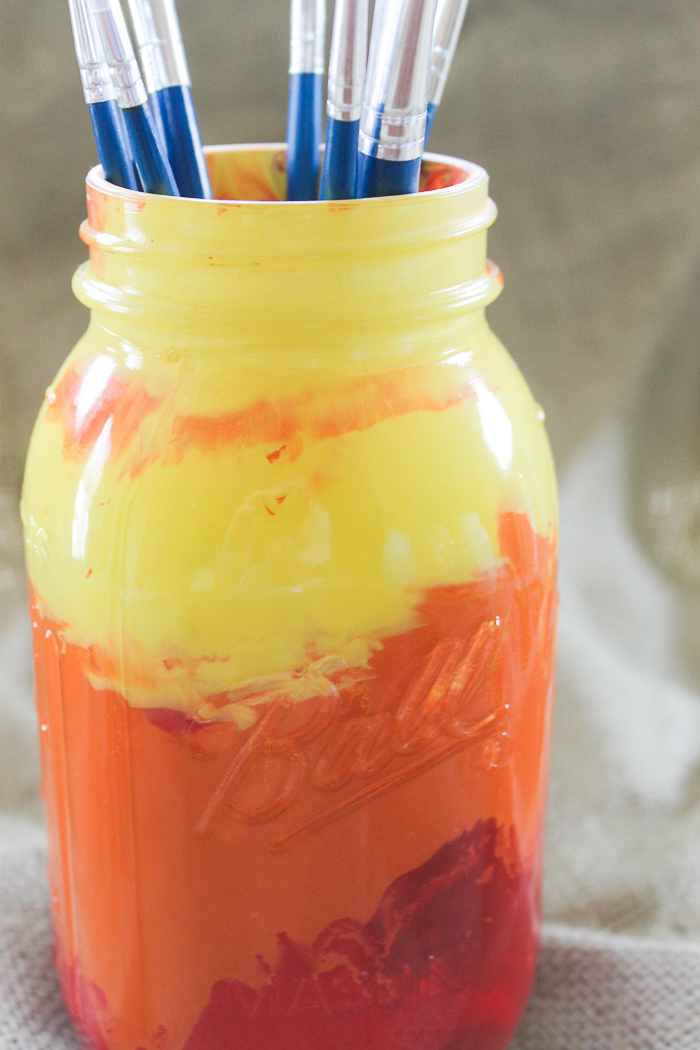 Drip the different red, orange, and yellow paints inside the mason jar from darkest to light