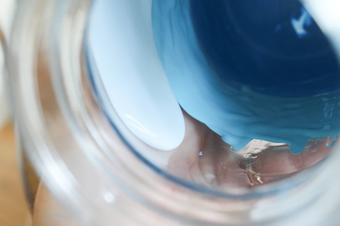 Add the lightest color of blue acrylic paint to the top third of the mason jar and swirl it around