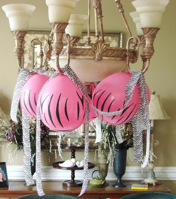 pink zebra balloons with zebra streamers hanging from a chandelier