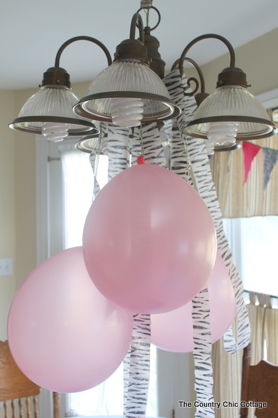pink balloons and zebra streamers hanging from kitchen light