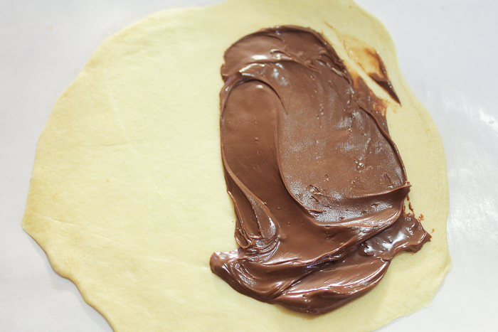 Spreading Nutella on flaky biscuit dough to make Nutella fried pies.