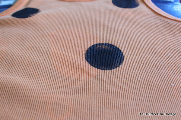 black painted polka dots on an orange tank top