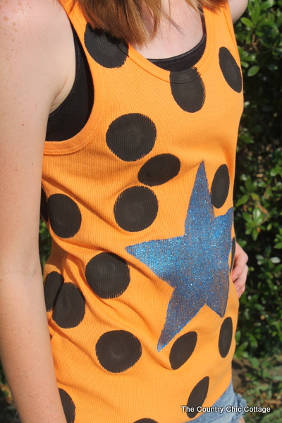 close up of orange tank top painted with black polka dots and blue shimmery star