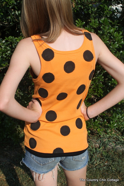 back of girl wearing orange tank top with black polka dots