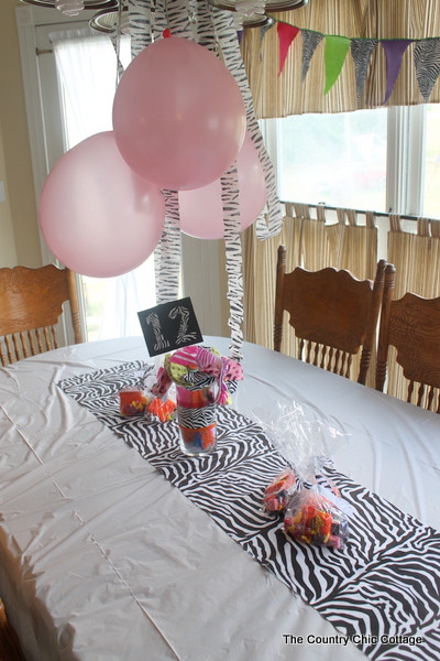 Zebra Themed Party table with pink balloons hanging from a chandelier