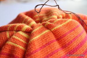 orange sweater with needle and thread
