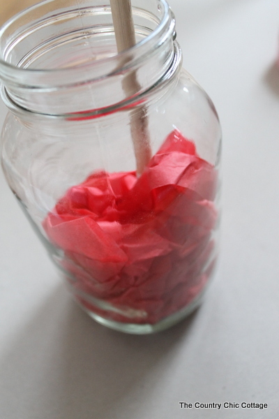 using a dowel to push tissue paper down into a glass jar