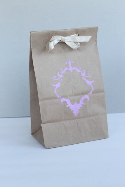 Purple design stenciled on brown bag with white ribbon