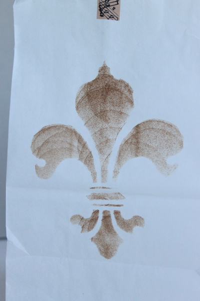 fleur de lis design stenciled on white bag