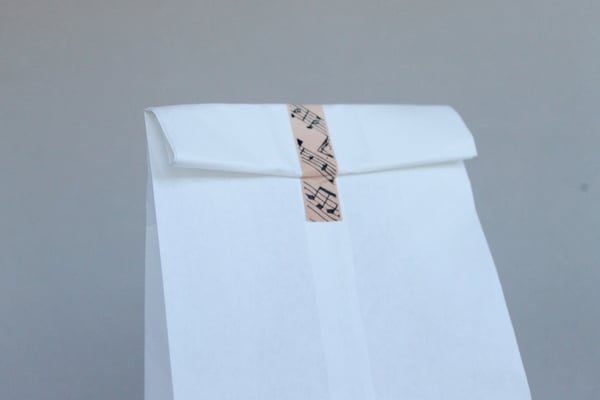 DIY Stenciled Wedding Favor Bags washi tape holding white bag closed