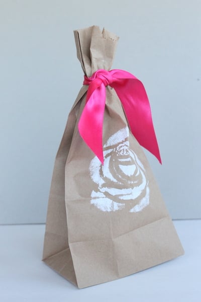 DIY Stenciled Wedding Favor Bags brown bag with white rose stencil and pink ribbon