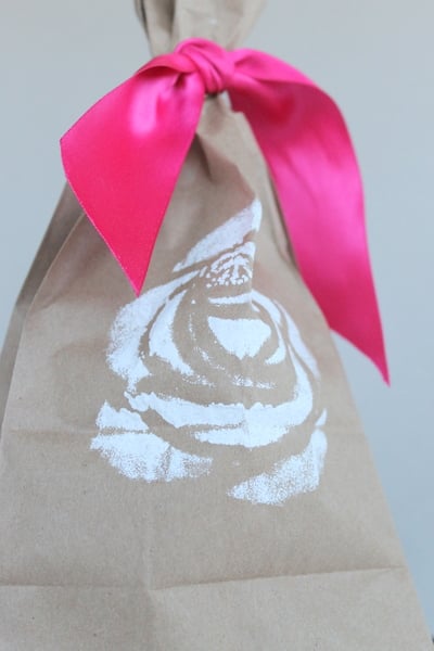 DIY Stenciled Wedding Favor Bags brown bag with white rose stencil and pink ribbon