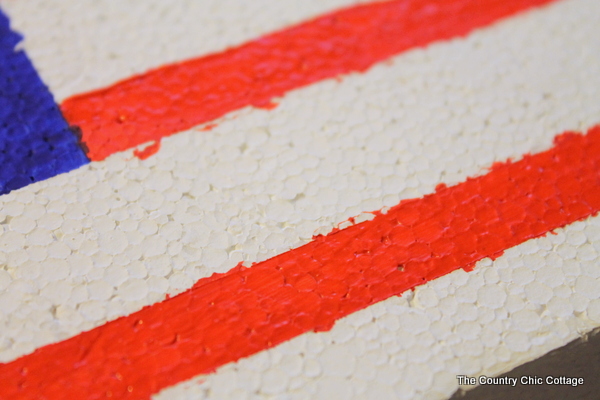 Make an American flag from foam for your patriotic decor this summer. A super simple project that only takes minutes to complete. foam block painted with red stripes and blue corner