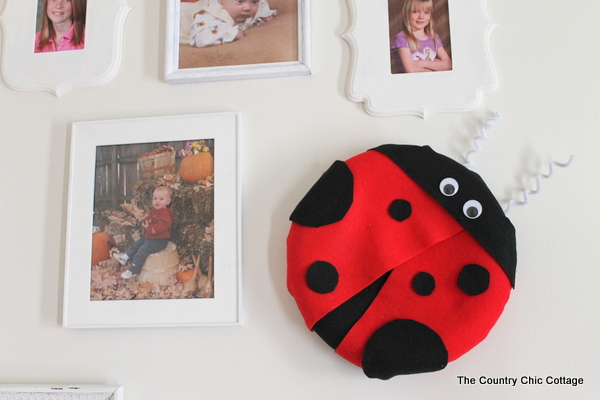 A lady bug shaped wreath would be a fun addition to a kids room or your front door for the summer! a lady bug shaped wreath on wall