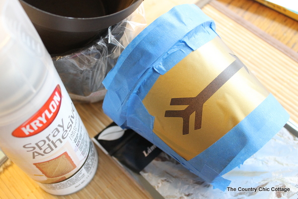 Add a gold leaf touch to metal flower pots with this easy to follow tutorial. Gold leaf is easy to use and makes a bold statement. Metal flower pot with vinyl and painter's tape applied.