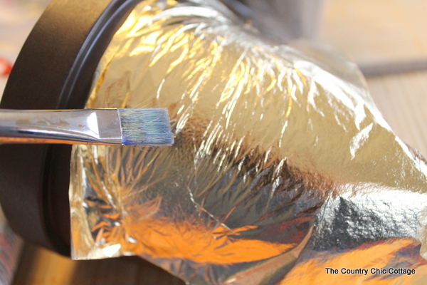 Add a gold leaf touch to metal flower pots with this easy to follow tutorial. Gold leaf is easy to use and makes a bold statement. Use a soft paintbrush to apply gold leaf to adhesive.