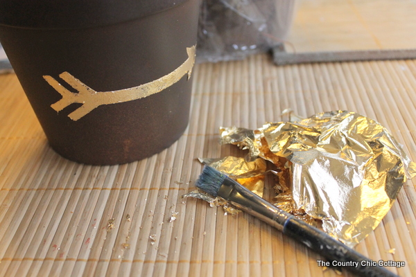 Add a gold leaf touch to metal flower pots with this easy to follow tutorial. Gold leaf is easy to use and makes a bold statement. Gold leaf design on metal flower pot with gold leaf scraps.