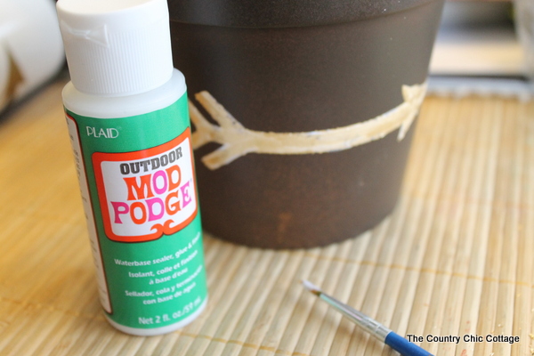 Add a gold leaf touch to metal flower pots with this easy to follow tutorial. Gold leaf is easy to use and makes a bold statement. Finished gold leaf metal flower pot with outdoor Mod Podge.