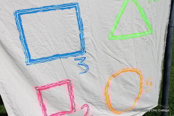 Glow in the Dark Yard Game -- make a summer of fun memories by adding yard games to your backyard or party. This glow in the dark game does not have to stop when the sun goes down! painting shapes and numbers on dropcloth